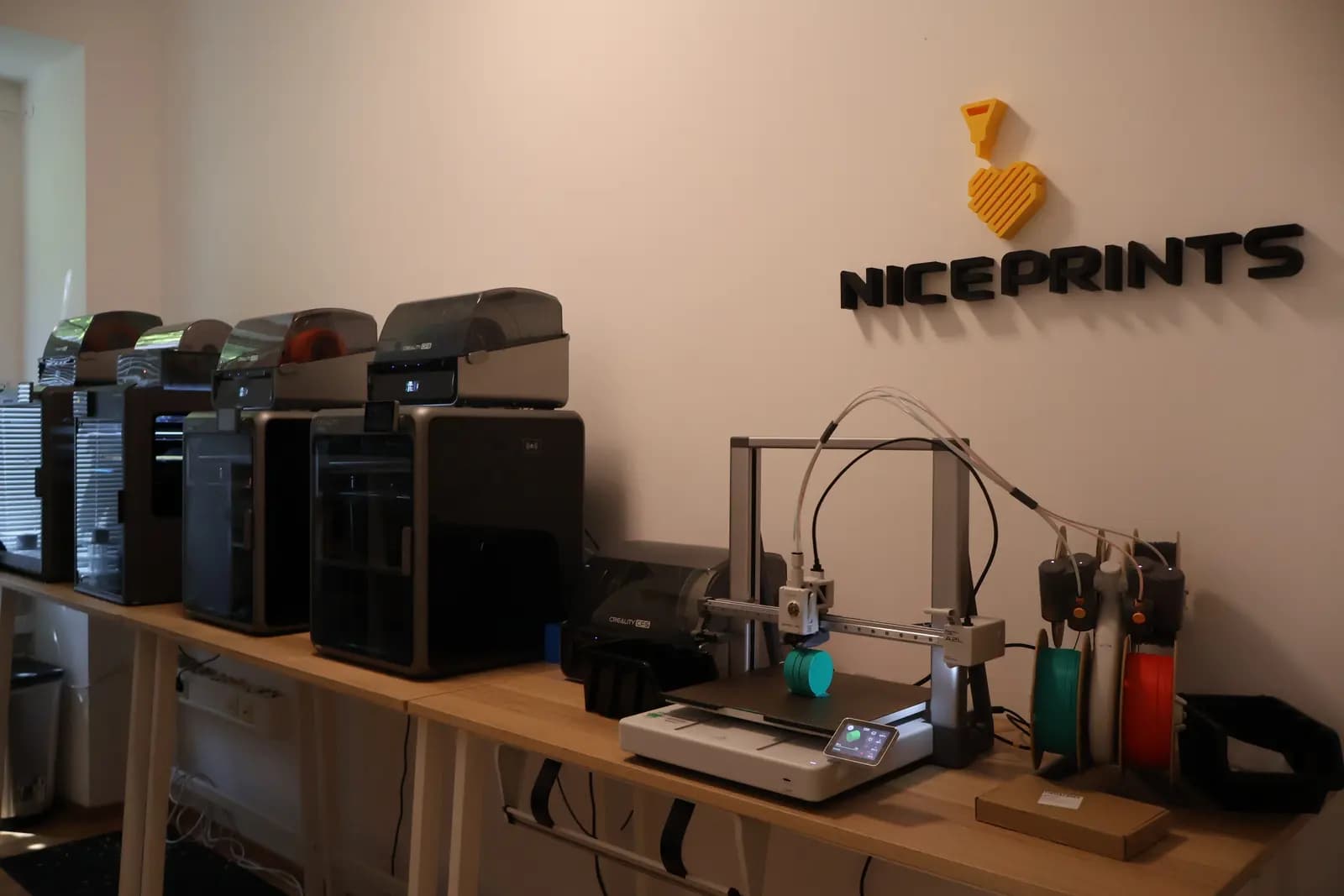 Niceprints Workspace in Wien mit 3D-Druckern und Niceprints-Logo an der Wand